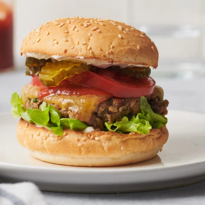 a hamburger with lettuce tomato ketchup and pickles on a white plate