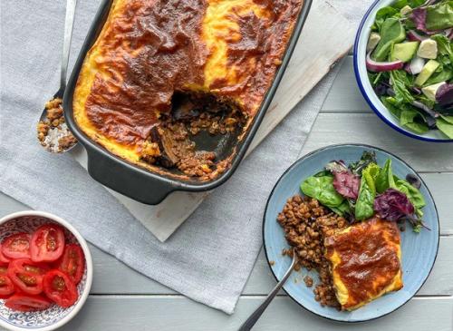 A golden-brown baked casserole, served with lentils, a fresh green salad, and sliced tomatoes. A golden-brown baked casserole, served with lentils, a fresh green salad, and sliced tomatoes.