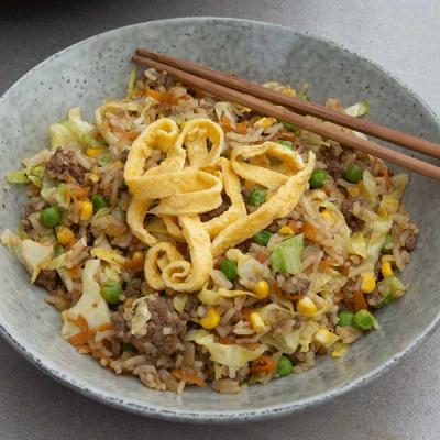 A bowl of fried rice with mince meat, peas, corn, cabbage, and egg strips, with chopsticks. A bowl of fried rice with mince meat, peas, corn, cabbage, and egg strips, with chopsticks.