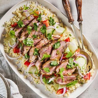 a white plate topped with meat on a bed of salad.
