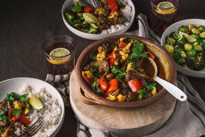a table topped with bowls of food and a bowl of curry . a table topped with bowls of food and a bowl of curry .