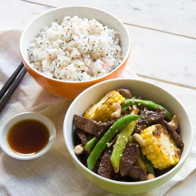 Beef stir-fry with green beans, grilled corn, and cashews, served with sesame rice and soy sauce. Beef stir-fry with green beans, grilled corn, and cashews, served with sesame rice and soy sauce.