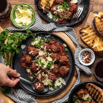 a person is holding a spoon over a plate of meatballs . a person is holding a spoon over a plate of meatballs .