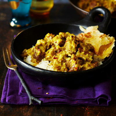 a bowl of food is sitting on a purple napkin on a table . a bowl of food is sitting on a purple napkin on a table .