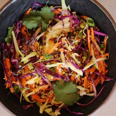 a close up of a bowl of Asian style slaw sitting on a table. a close up of a bowl of Asian style slaw sitting on a table.
