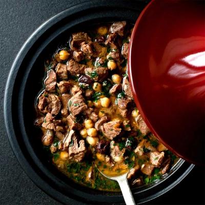 a bowl of stew with lamb and chickpeas in a pot with a spoon .