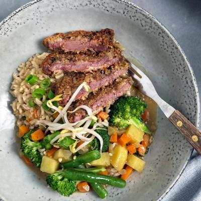 Breaded steak slices, brown rice, mixed vegetables, and bean sprouts in a speckled bowl with a fork.