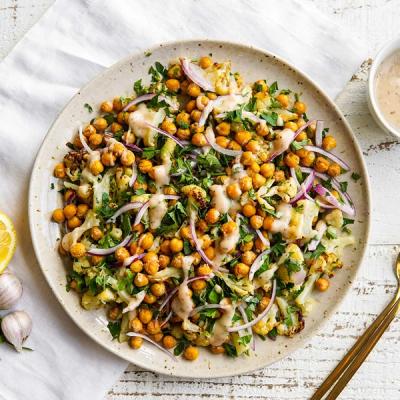 a plate of food with chickpeas , cauliflower , and onions on a table . a plate of food with chickpeas , cauliflower , and onions on a table .