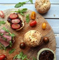 a wooden cutting board topped with a variety of sandwiches and tomatoes a wooden cutting board topped with a variety of sandwiches and tomatoes