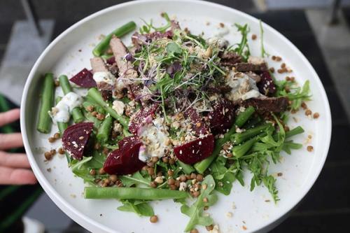 Salad with sliced steak, beetroot, green beans, rocket, lentils, crumbled cheese, and microgreens.