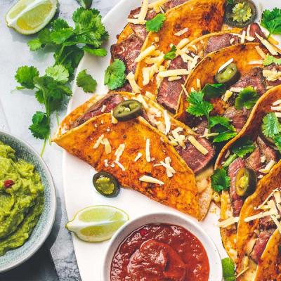a plate of tacos with guacamole and salsa on a table . a plate of tacos with guacamole and salsa on a table .