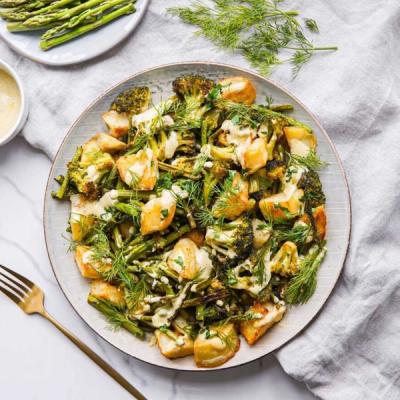 a plate of food with broccoli , potatoes , asparagus and dill on a table with a fork . a plate of food with broccoli , potatoes , asparagus and dill on a table with a fork .