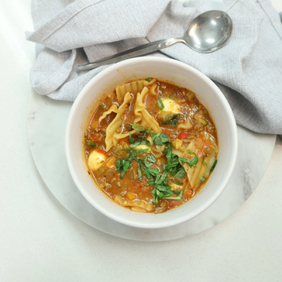 a bowl of soup with noodles and a spoon in it a bowl of soup with noodles and a spoon in it