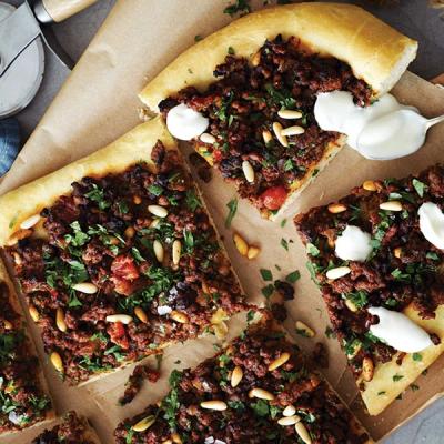 a pizza with a lot of toppings on it is sitting on a table. a pizza with a lot of toppings on it is sitting on a table.