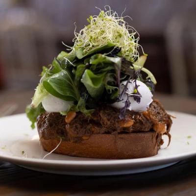Shredded meat on toast topped with poached eggs, mixed greens, and sprouts. Shredded meat on toast topped with poached eggs, mixed greens, and sprouts.
