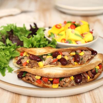 a plate of food on a table with quesadillas stuffed with lamb and beans and a side salad. a plate of food on a table with quesadillas stuffed with lamb and beans and a side salad.