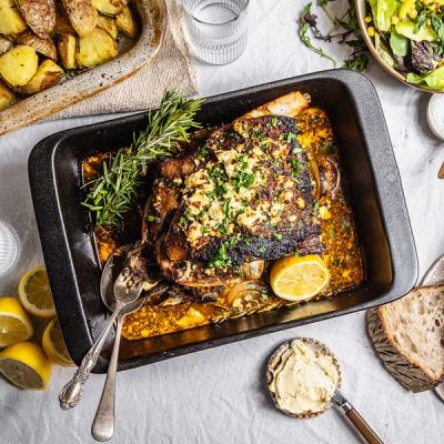 a casserole dish filled with roast lamb and potatoes on a table .