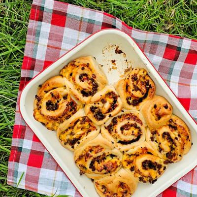 a pan of pizza rolls is sitting on a plaid towel on the grass . a pan of pizza rolls is sitting on a plaid towel on the grass .