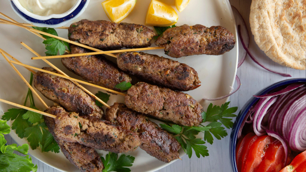 a white plate topped with meat skewers and vegetables a white plate topped with meat skewers and vegetables
