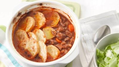 Meat and vegetable stew topped with browned potato slices, served with a green side salad. Meat and vegetable stew topped with browned potato slices, served with a green side salad.