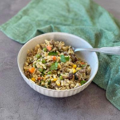 a bowl of pasta, mince and vegetables with a spoon in it .