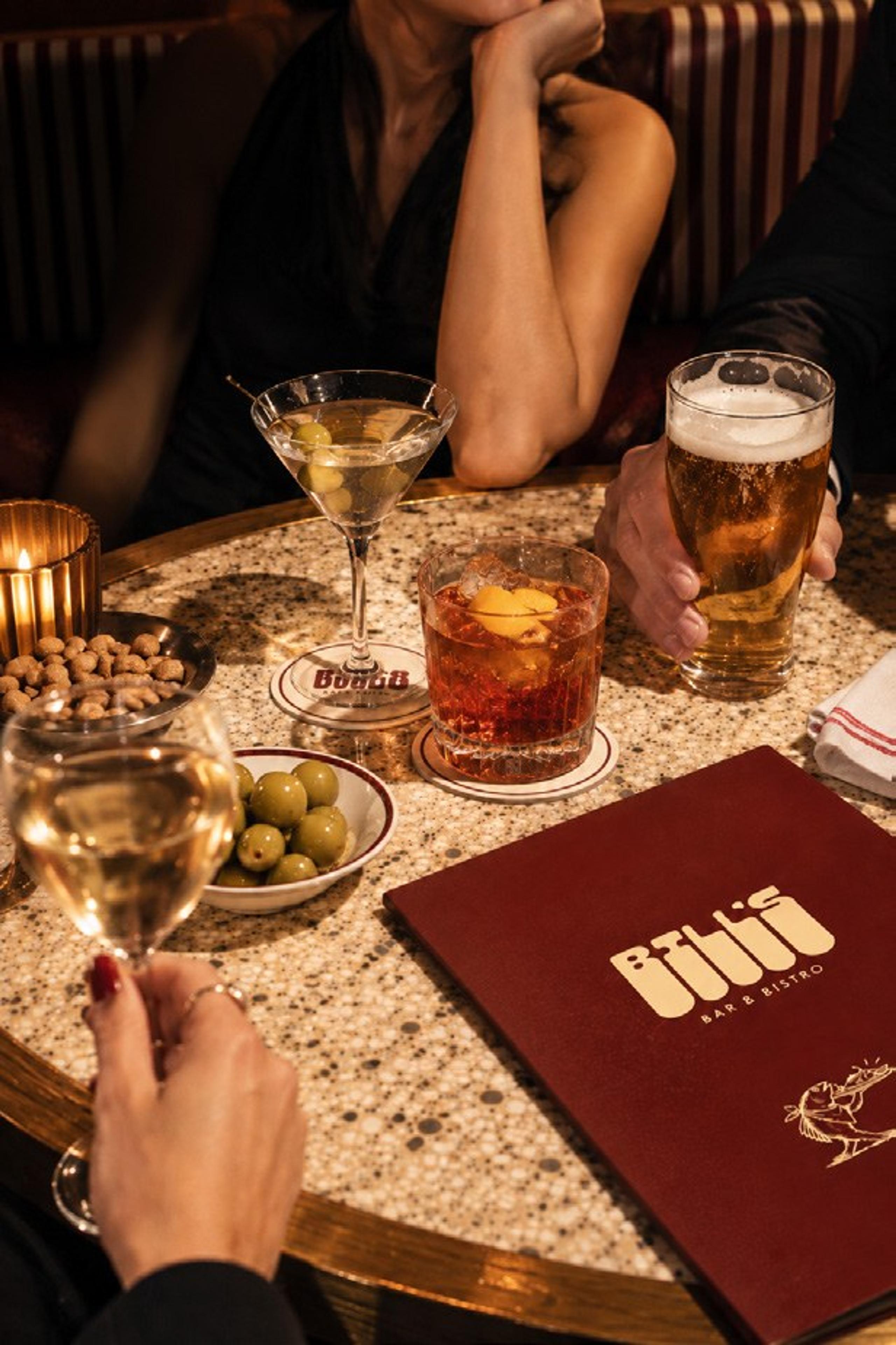 A martini, a negroni and a beer on a terrazzo table beside a Bill’s menu