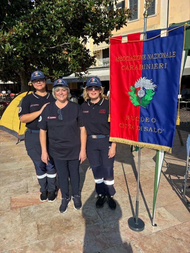 Tre volontarie in divisa ANC accanto al labaro ufficiale con stemma dell'Associazione Nazionale Carabinieri Nucleo Città di Salò
