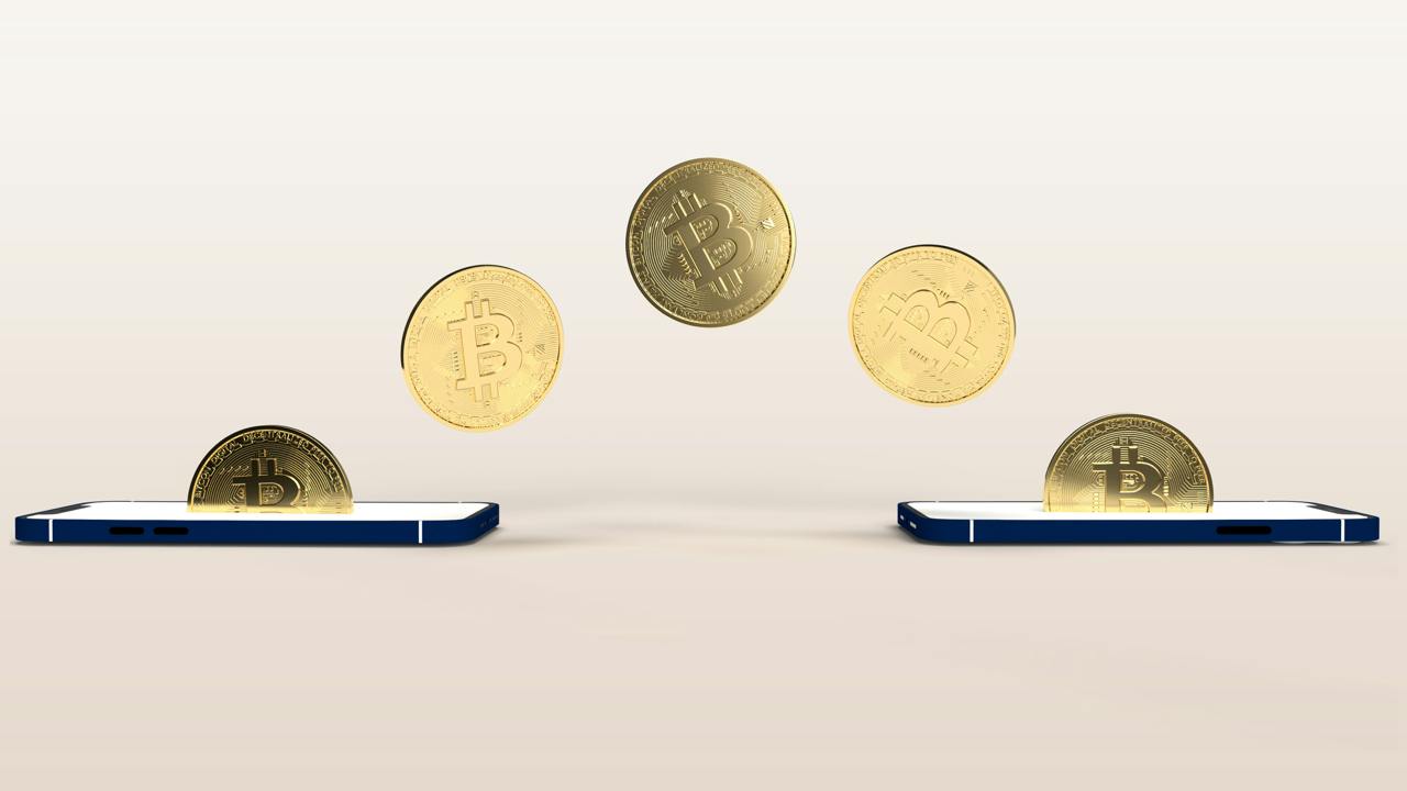 Two mobile phones exchanging physical coins of Bitcoin cryptocurrency
