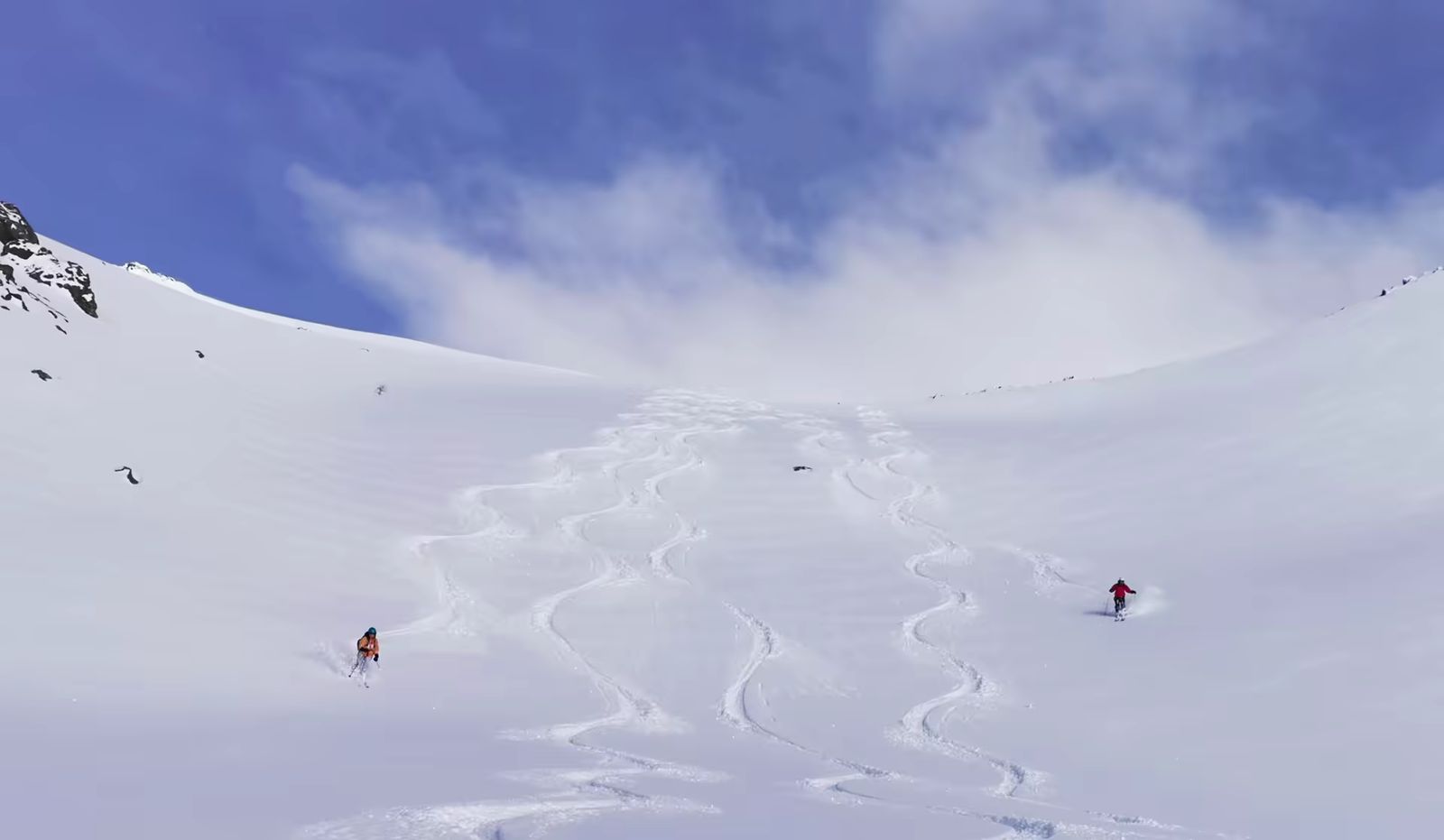 Skieurs descendant une large combe enneigée près de Montgenèvre