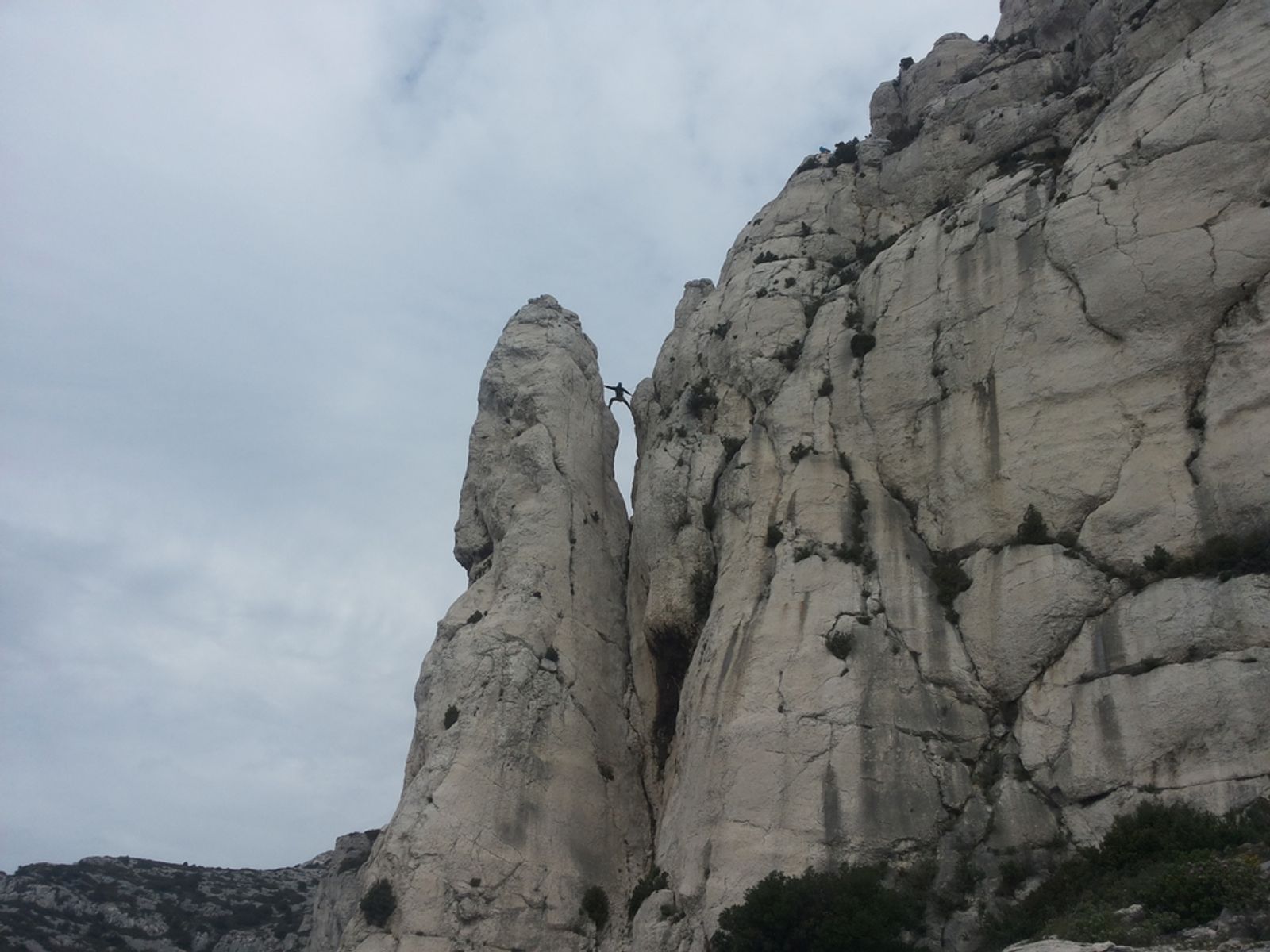 Grimpeur avec un sac à dos dans un passage raide du calcaire de la Candelle