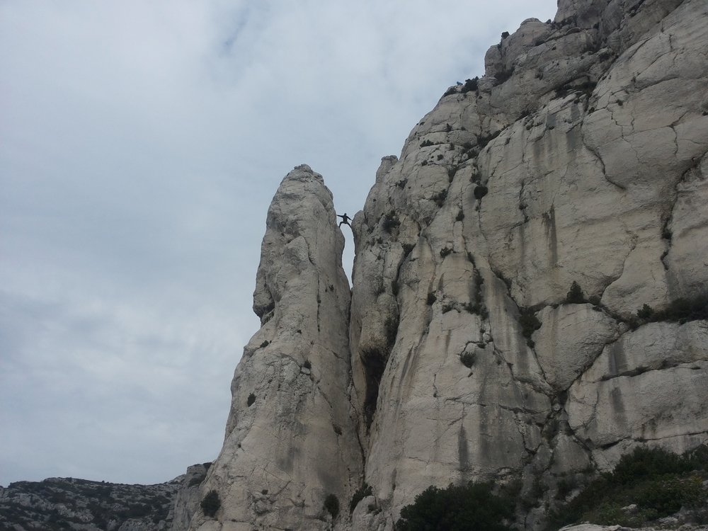 Grimpeur avec un sac à dos dans un passage raide du calcaire de la Candelle