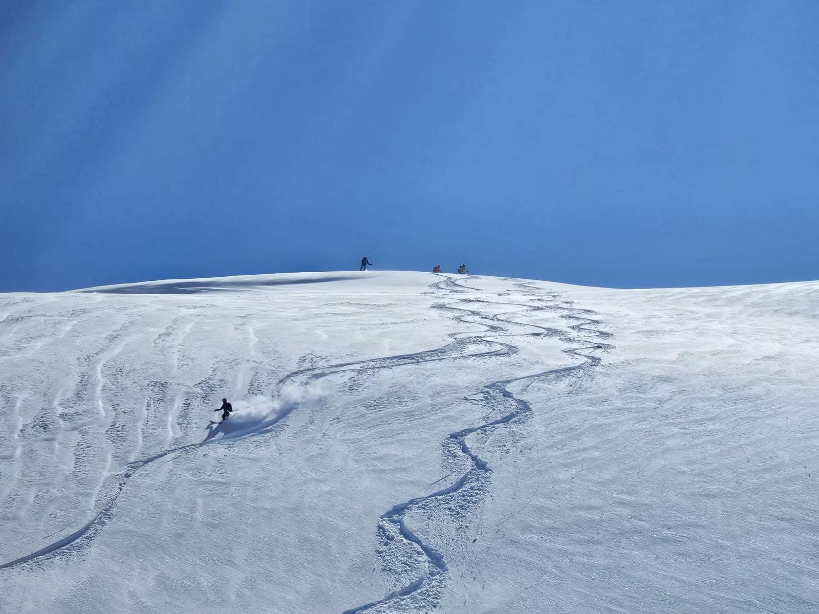 Skieur traçant une pente poudreuse sous un ciel bleu en Arménie