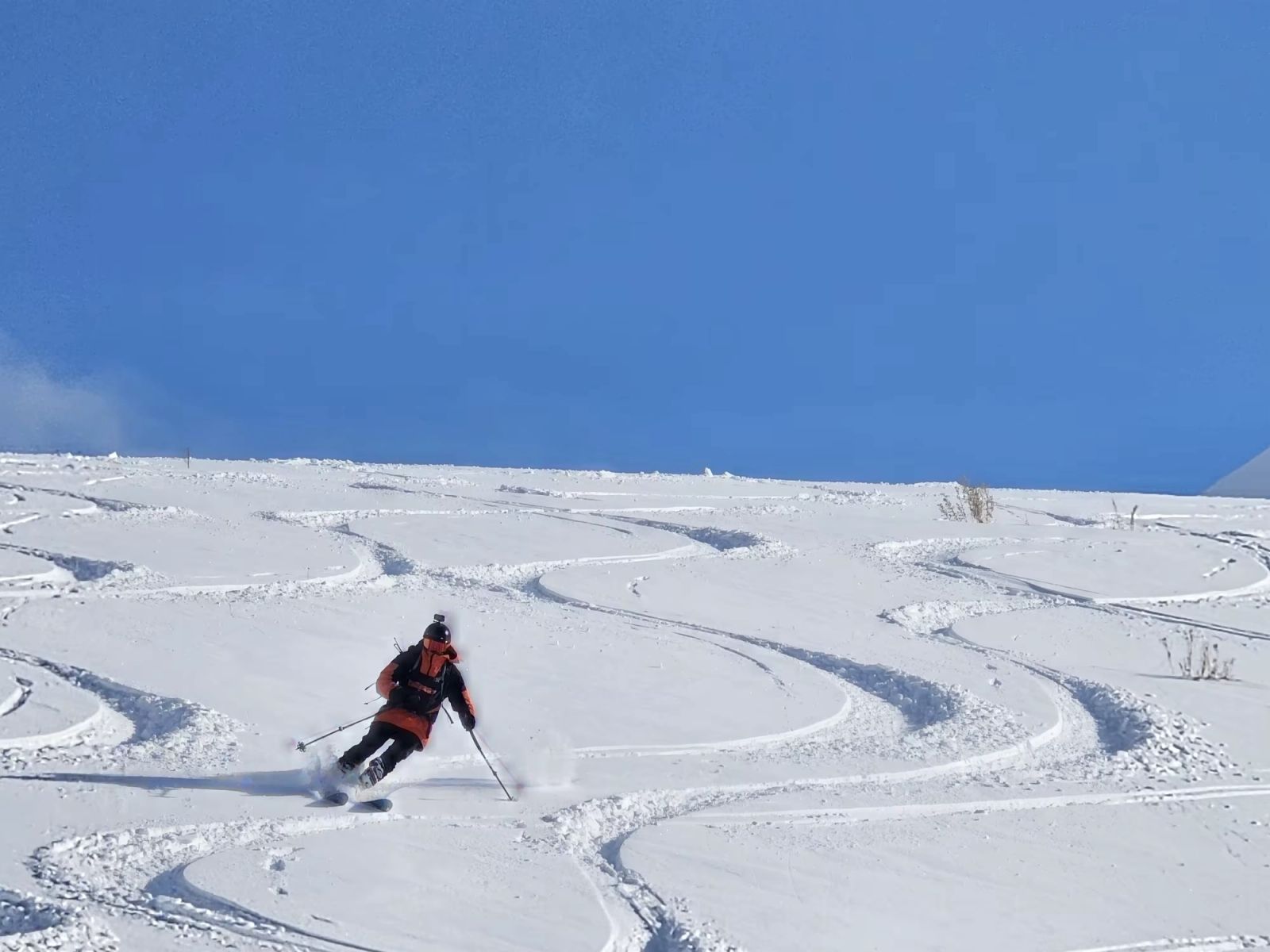 Skieur en veste rouge descendant une pente de poudreuse en Arménie