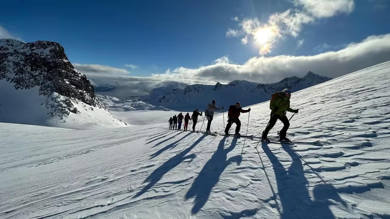 Groupe en montée à ski de randonnée au-dessus des fjords norvégiens