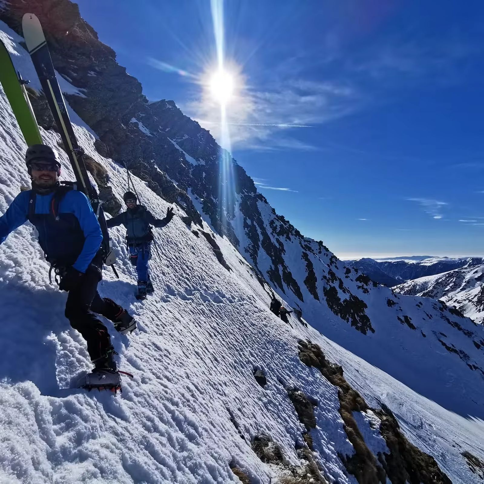Skieurs portant leurs skis dans un passage raide et ensoleillé du Mercantour