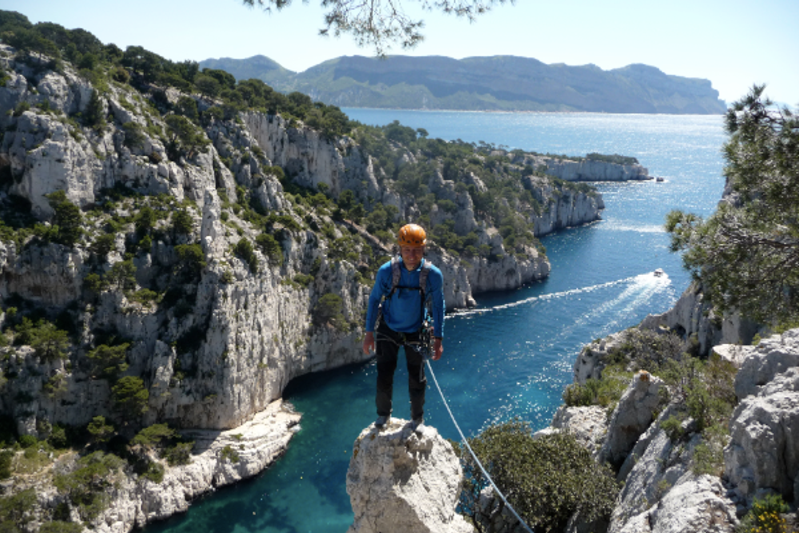 Grimpeur debout sur une pointe rocheuse au-dessus de la calanque d’En-Vau