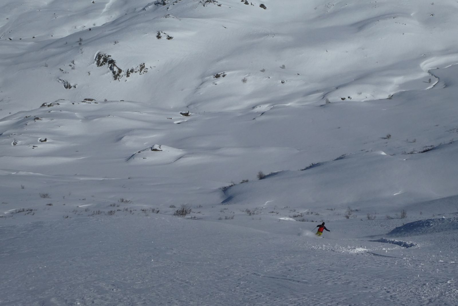 Skieur descendant une pente de poudreuse vers Terre Rouge