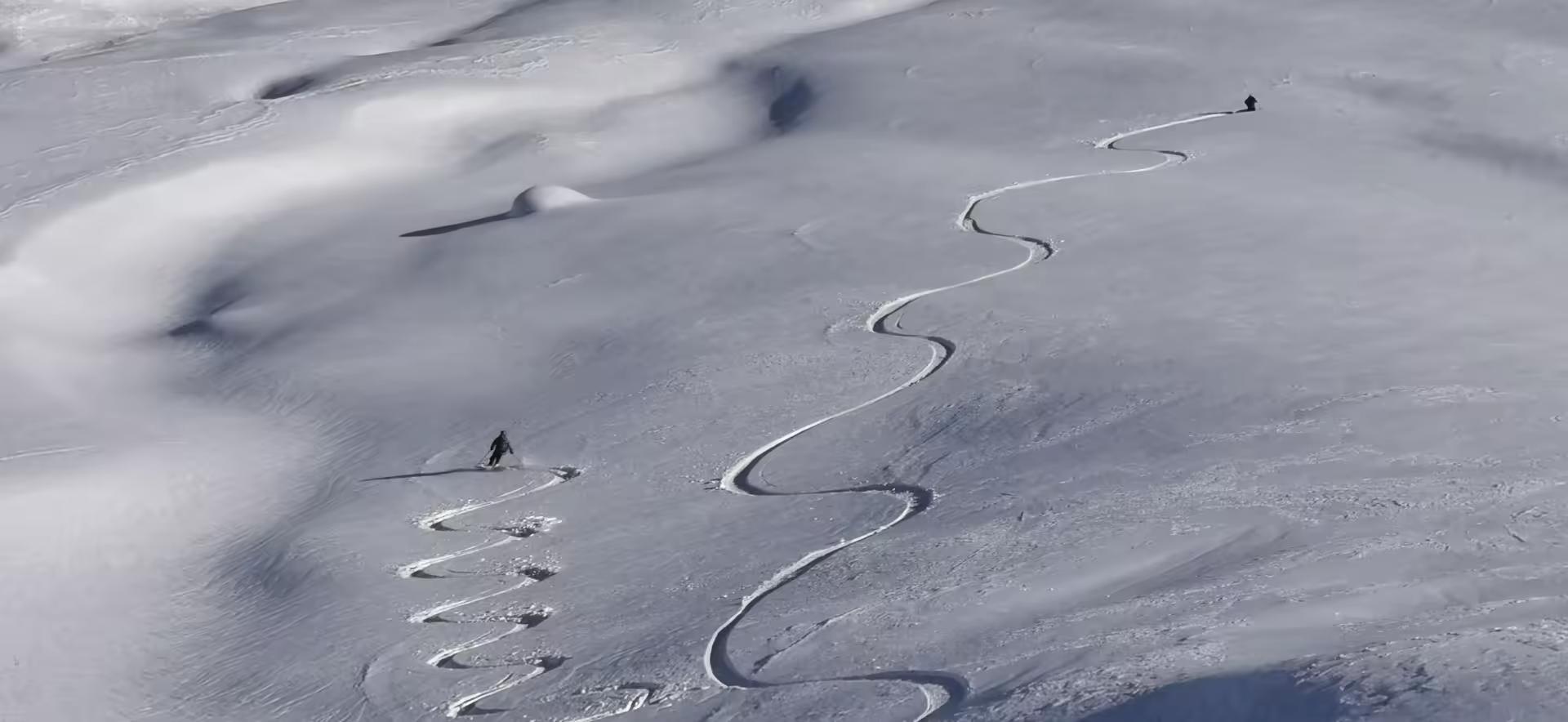 Dans les pentes sous la Rouya, deux skieurs tracent à la descente dans la poudreuse
