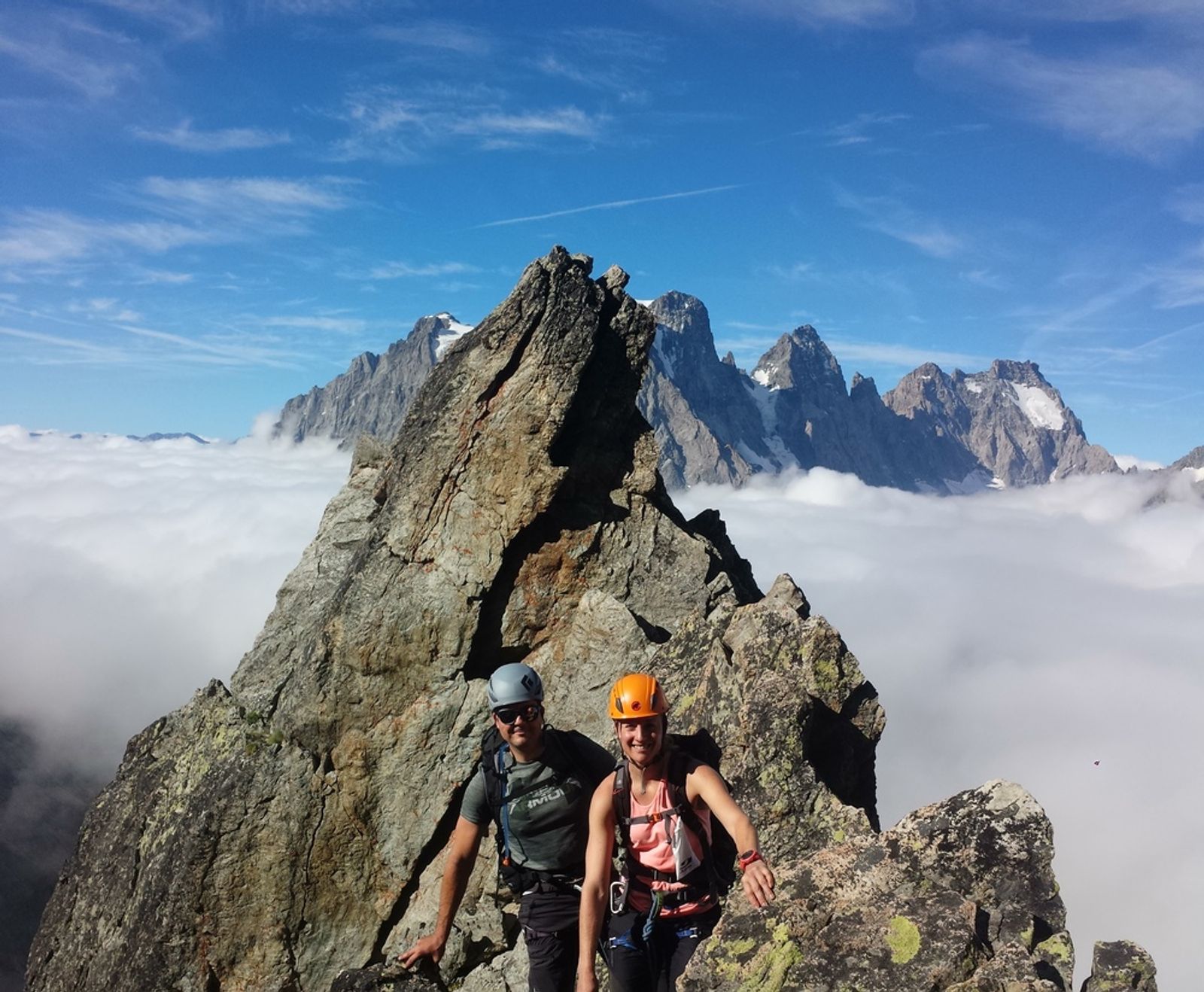 Nico et Caro sur l’arête des Cinéastes, devant un gendarme rocheux dominant une mer de nuages.