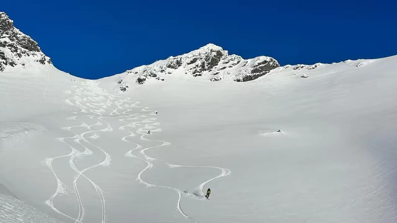 Skieur traçant une vaste pente de poudreuse pendant un voyage ski-voile en Norvège