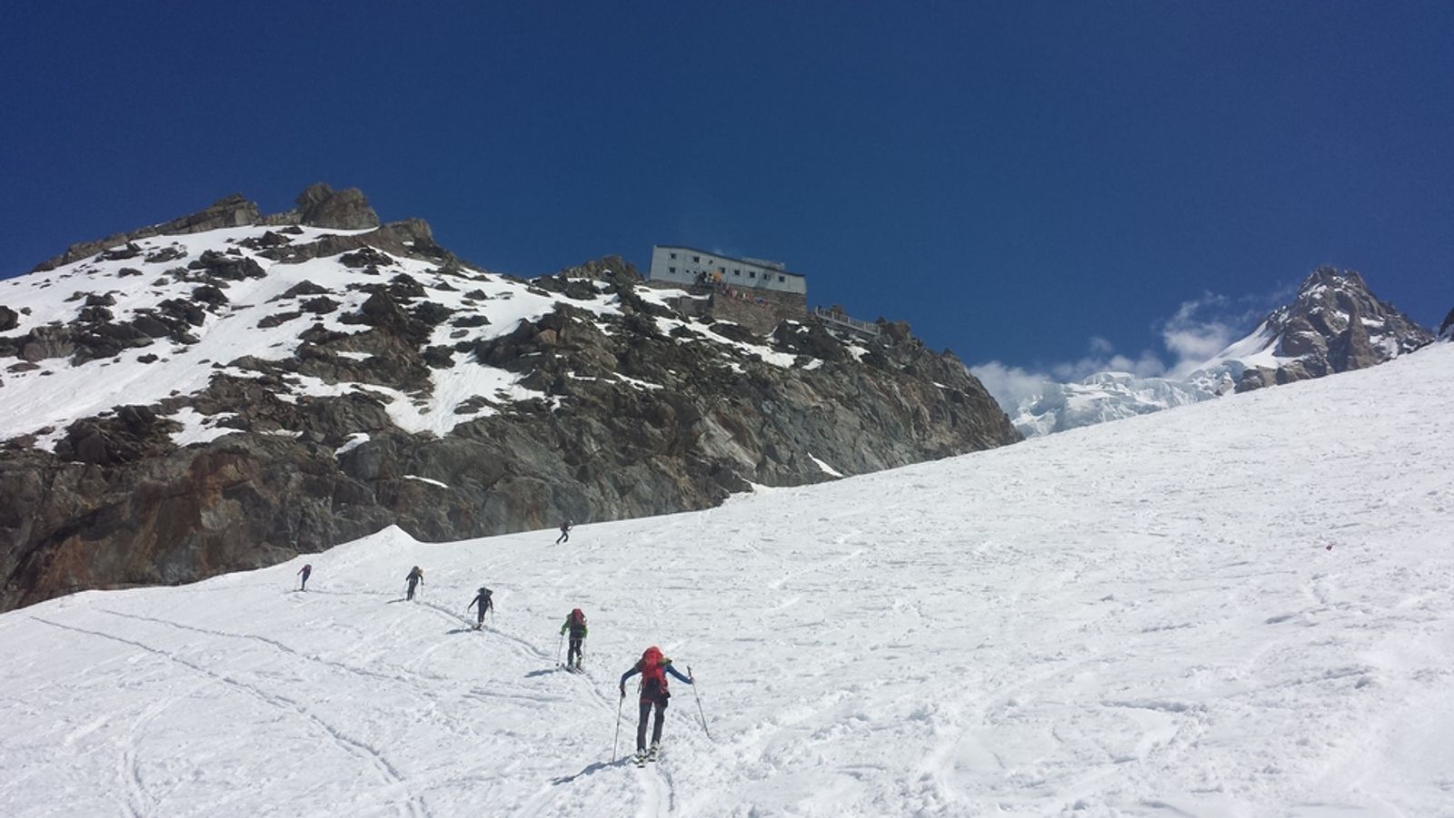 Skieurs montant vers le refuge des Grands Mulets, perché sur un éperon rocheux.