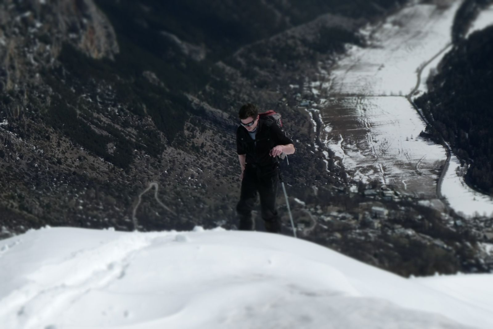 Skieur en train de montée à la Tête des Raisins avec la plaine de Freissinières tout en bas