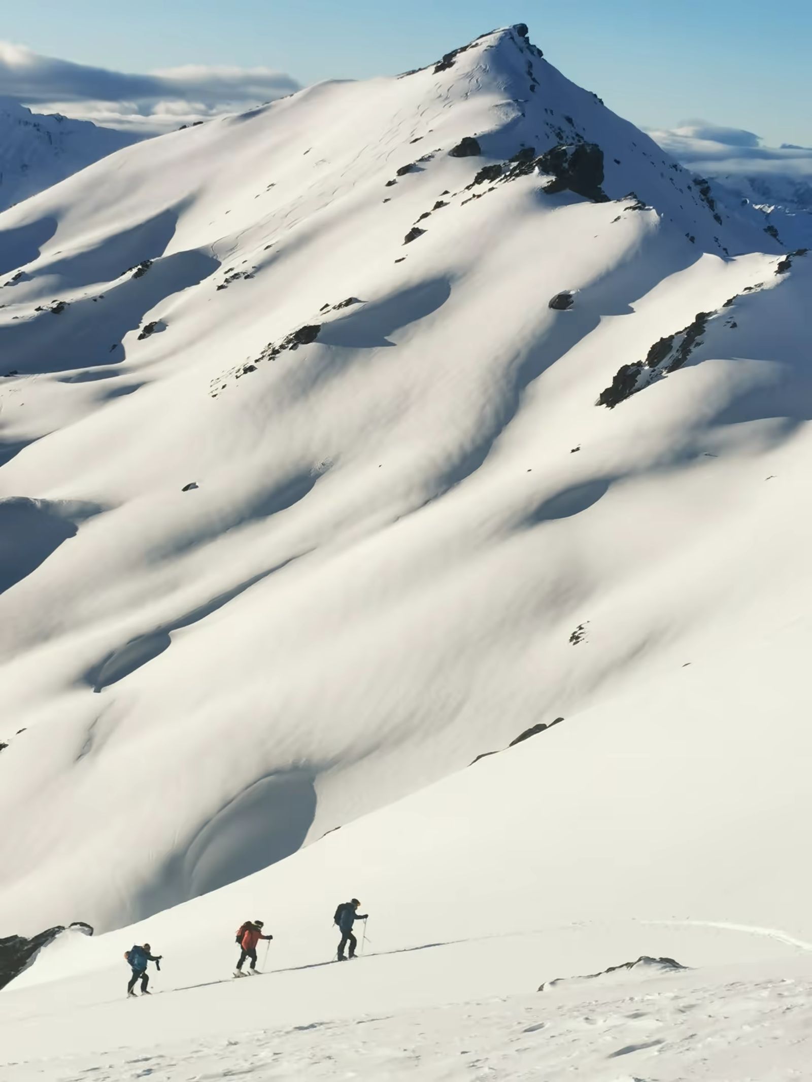 Skieurs progressant sous un sommet enneigé pendant un raid dans les Cerces