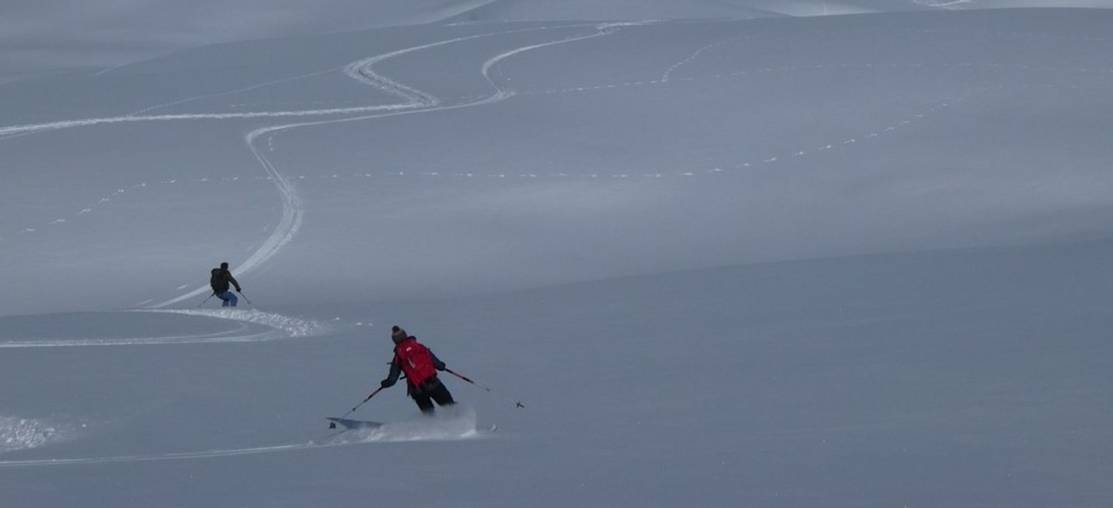 Deux skieurs traçant des virages dans la poudreuse sous la Blanche.
