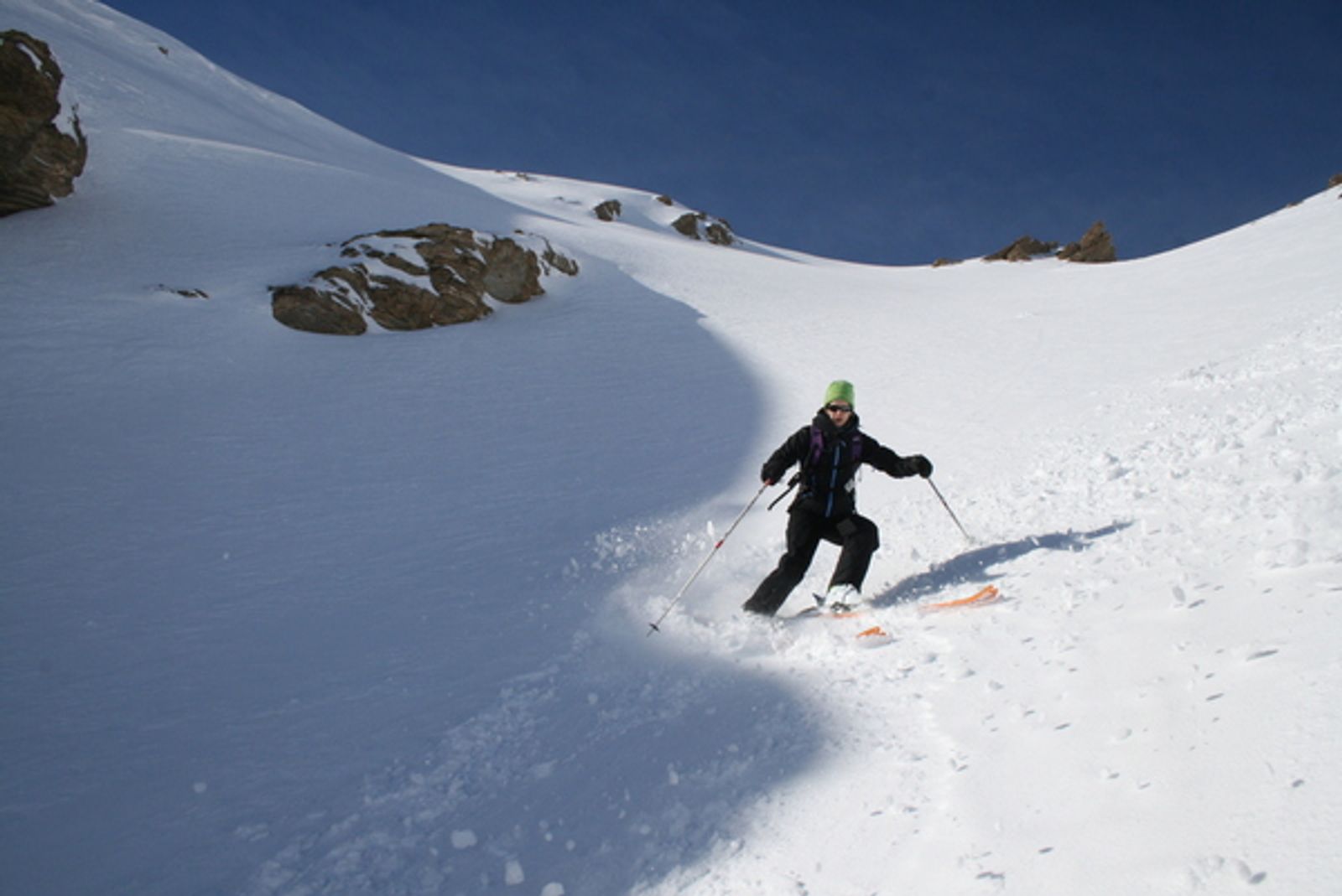 Skieur traçant un virage dans la poudreuse sous la Tête du Girardin.