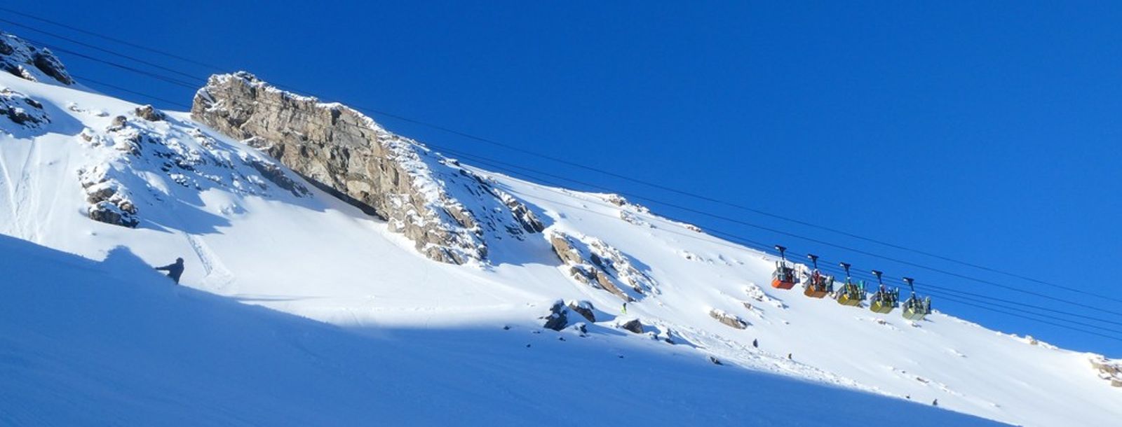 Pentes enneigées et barres rocheuses sous les câbles du téléphérique de La Grave.Pentes enneigées et barres rocheuses sous les câbles du téléphérique de La Grave.