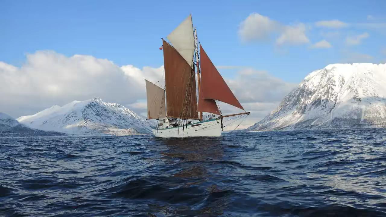 Le Fleur de Lampaul navigue sous voiles entre les montagnes enneigées de Norvège
