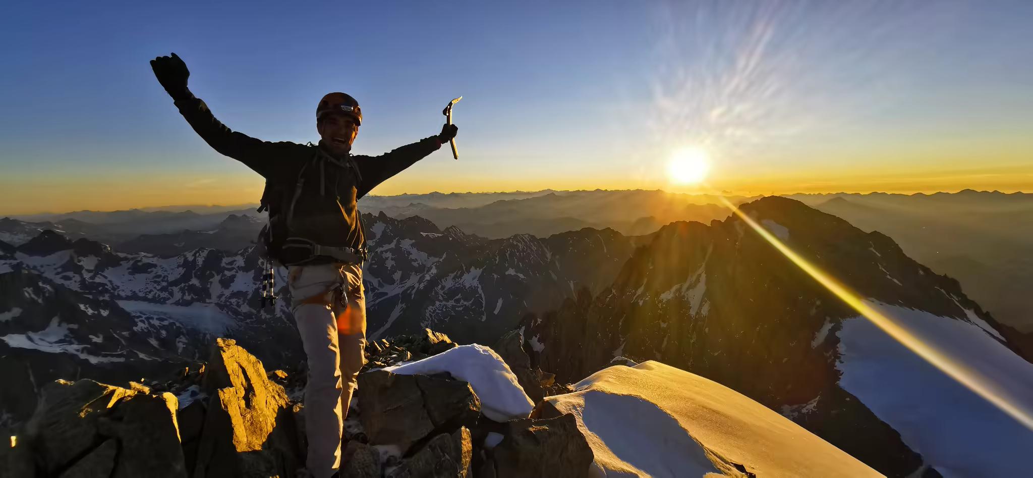 Alpiniste au sommet du Pelvoux face au lever du soleil dans le massif des Écrins