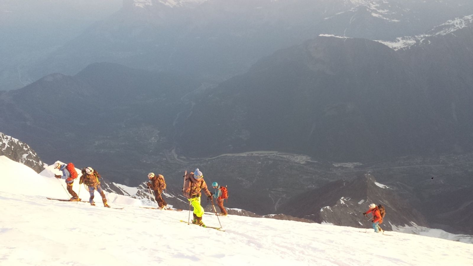 Groupe de skieurs remontant une pente enneigée du Mont-Blanc au-dessus de la vallée.