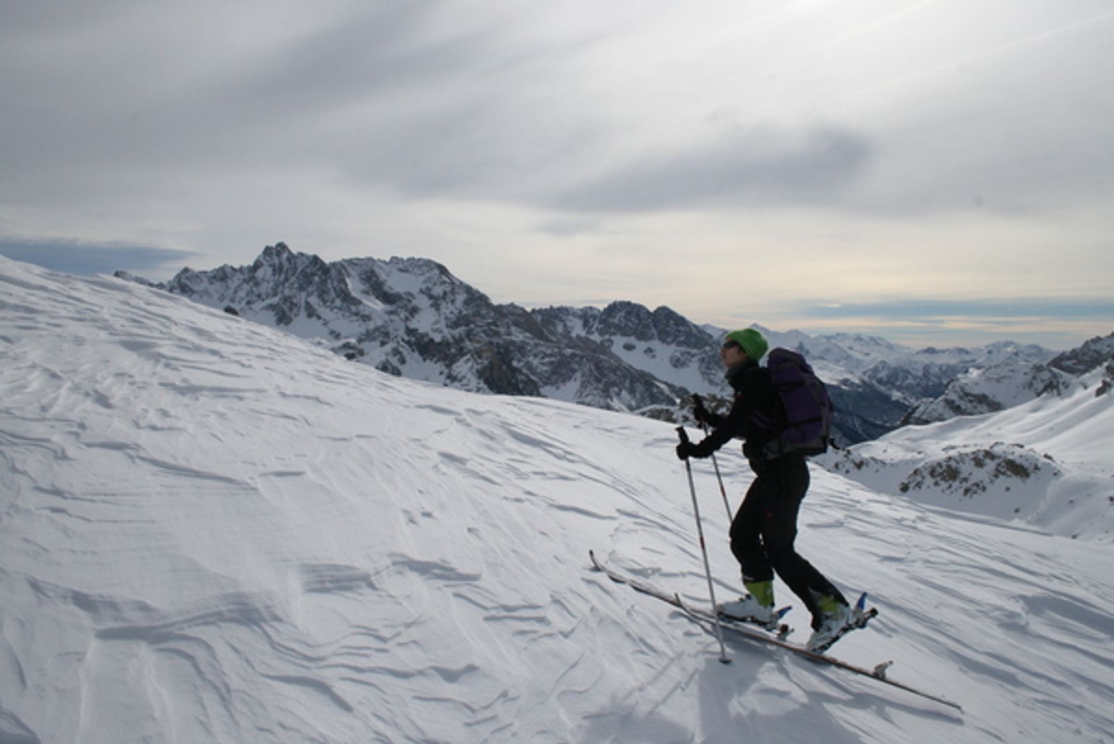 Skieur de randonnée progressant sur une pente de neige travaillée par le vent au Girardin.
